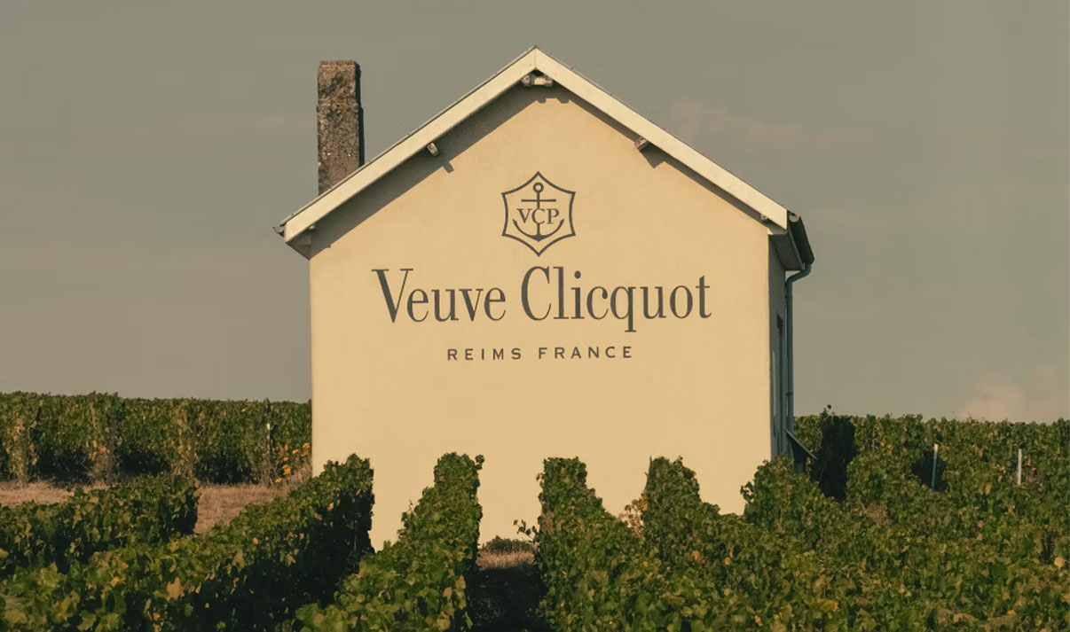 Veuve Clicquot Reims France text on house wall, surrounded by vineyard rows.