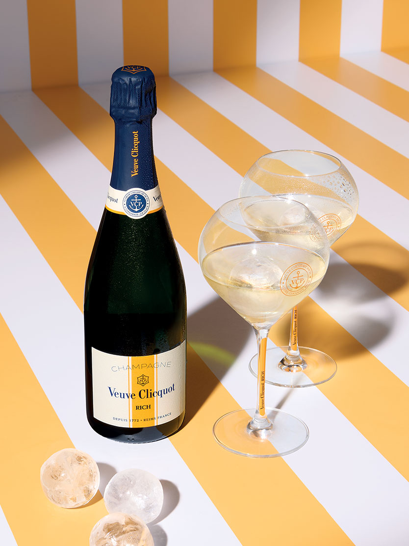 Veuve Clicquot Rich champagne bottle with two filled glasses and ice cubes.