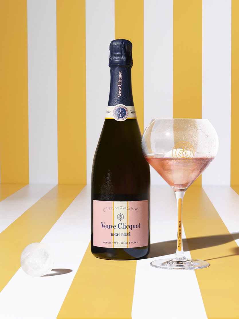 Veuve Clicquot rosé champagne bottle with filled glass and ice sphere.