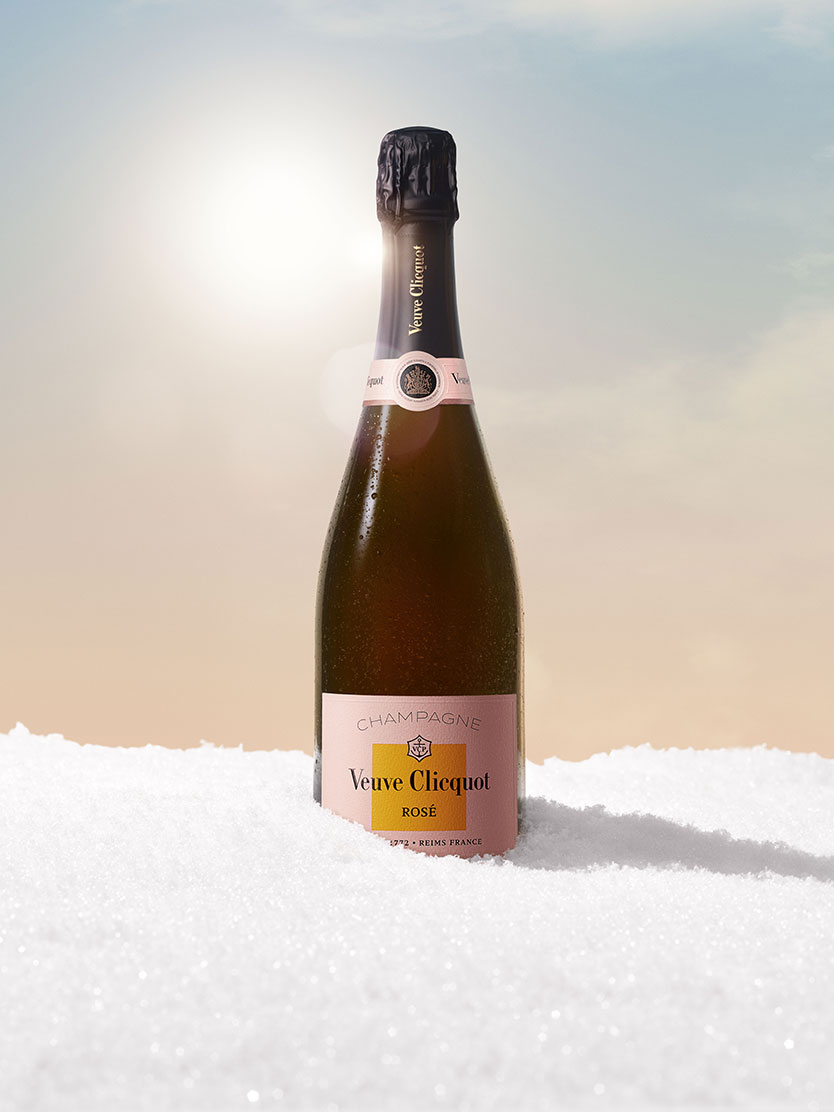 Veuve Clicquot Rosé champagne bottle standing upright in snow.