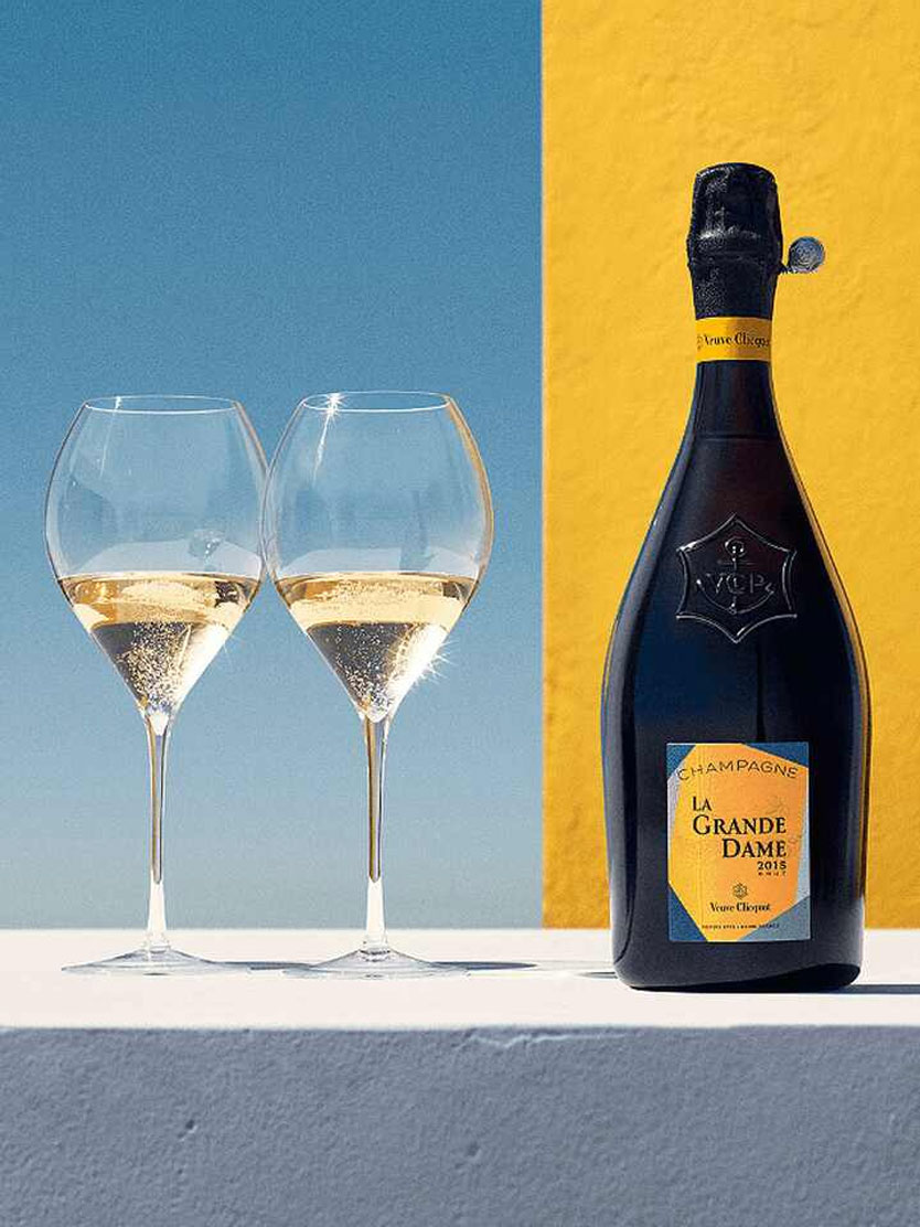 Two glasses of champagne with a bottle of La Grande Dame 2015.