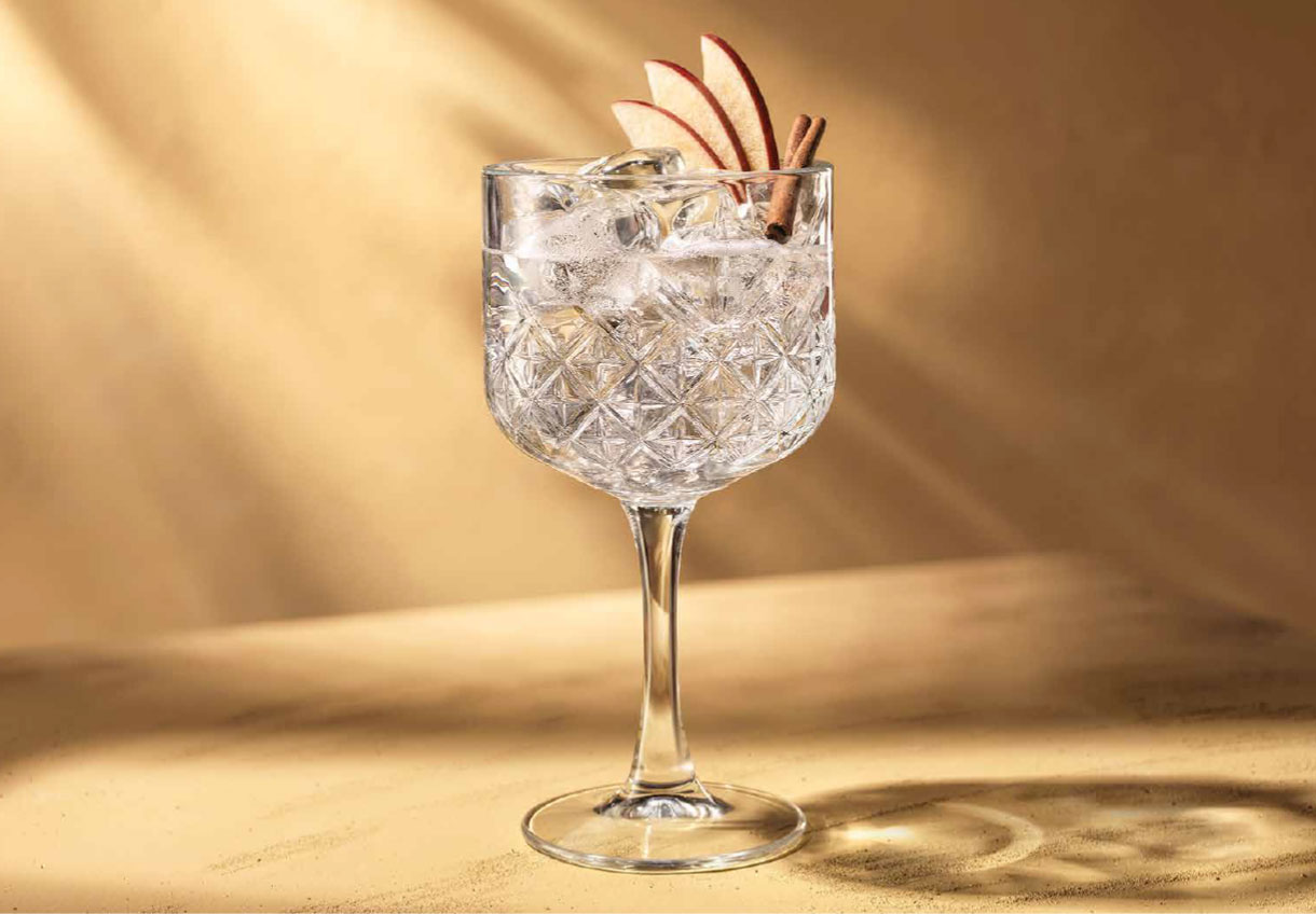 Crystal wine glass with ice and apple slices garnish.